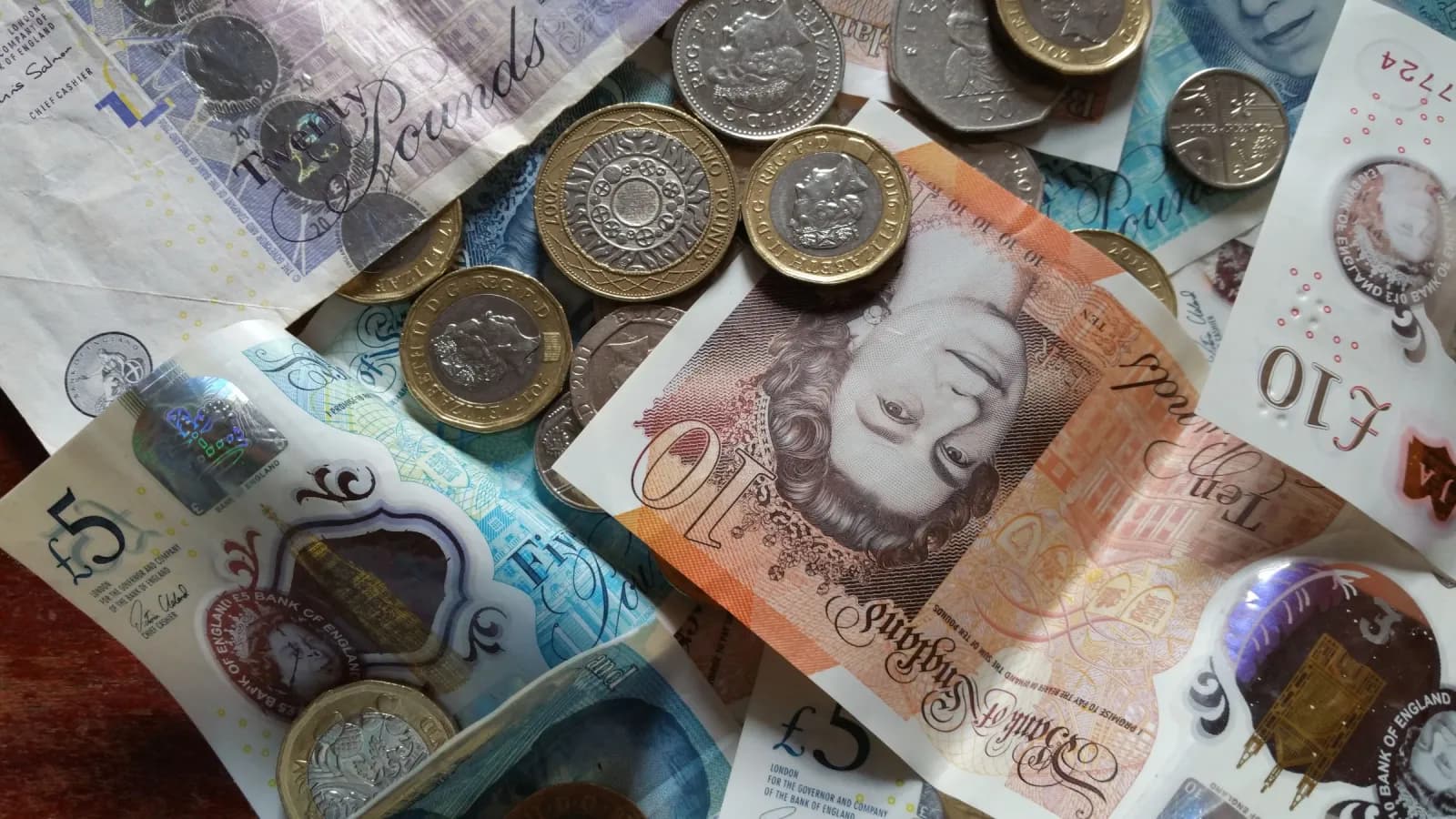 British pound notes and coins spread across a table