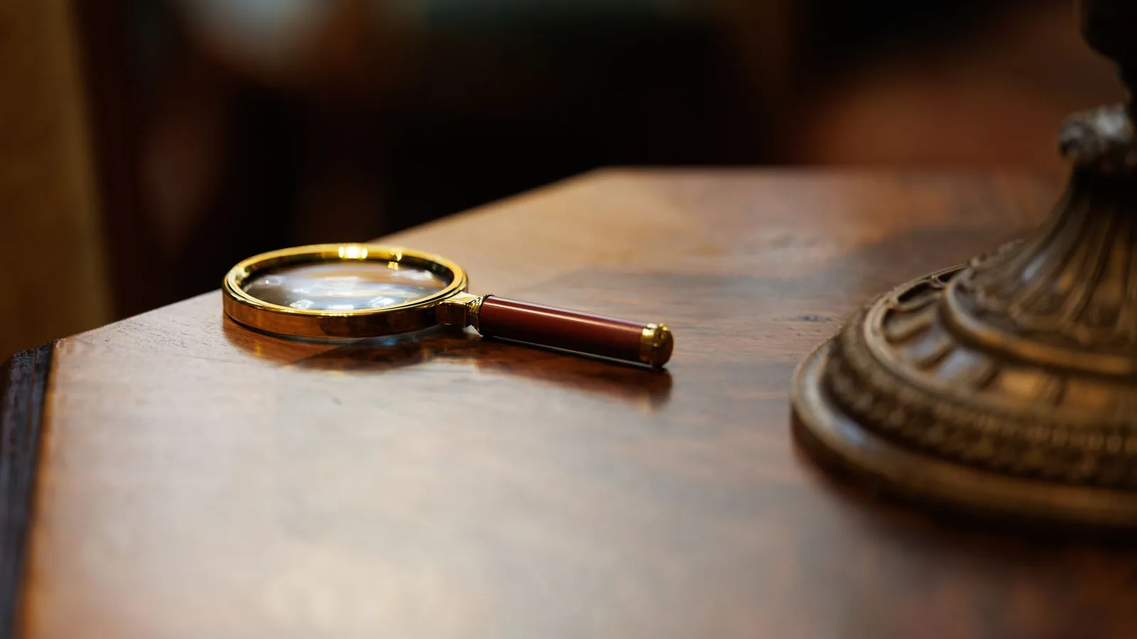A brass magnifying glass on a polished wooden desk