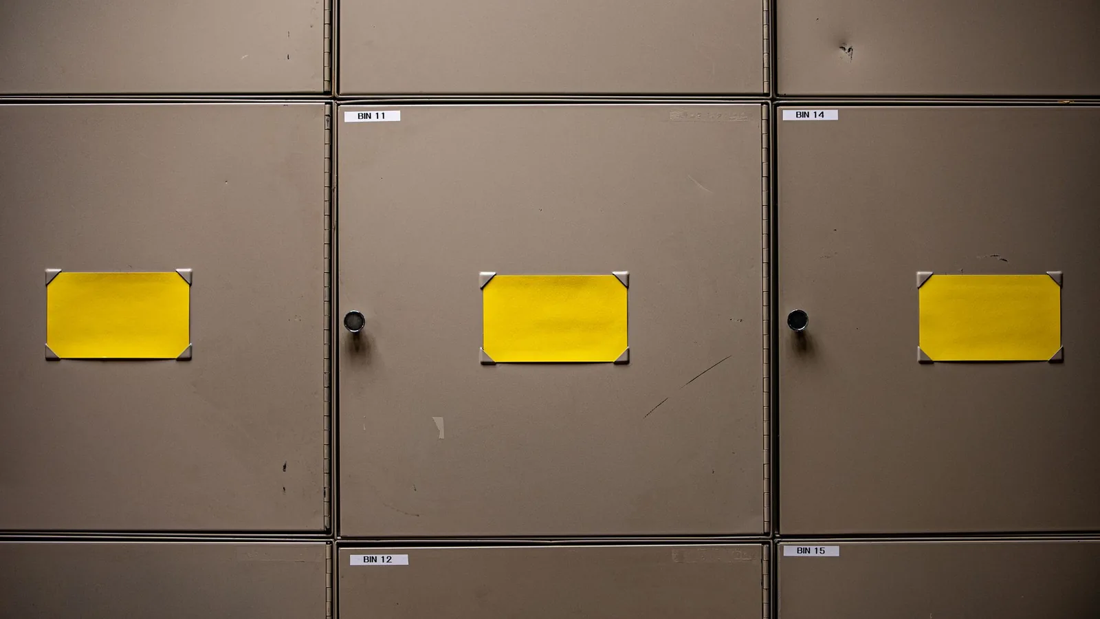 Grey metal storage cabinets with blank yellow labels on their doors